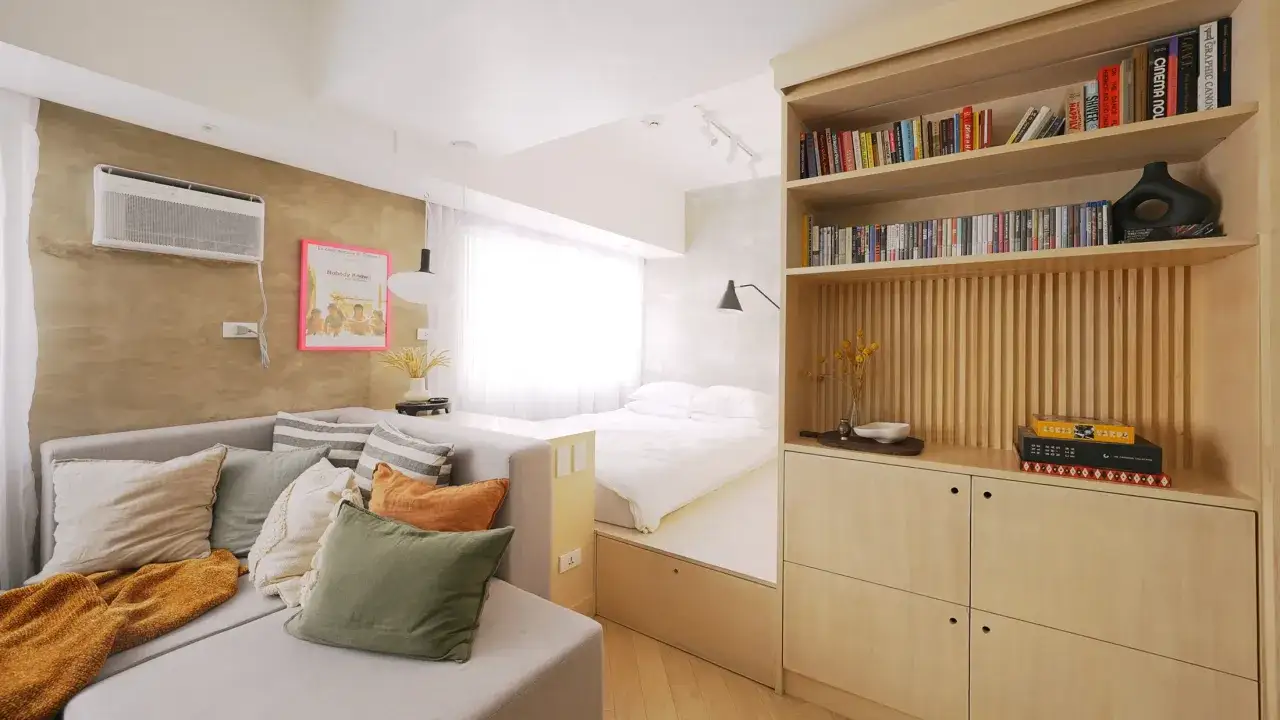Acogedora casa pequena con sofá, cama elevada y estantería de madera.