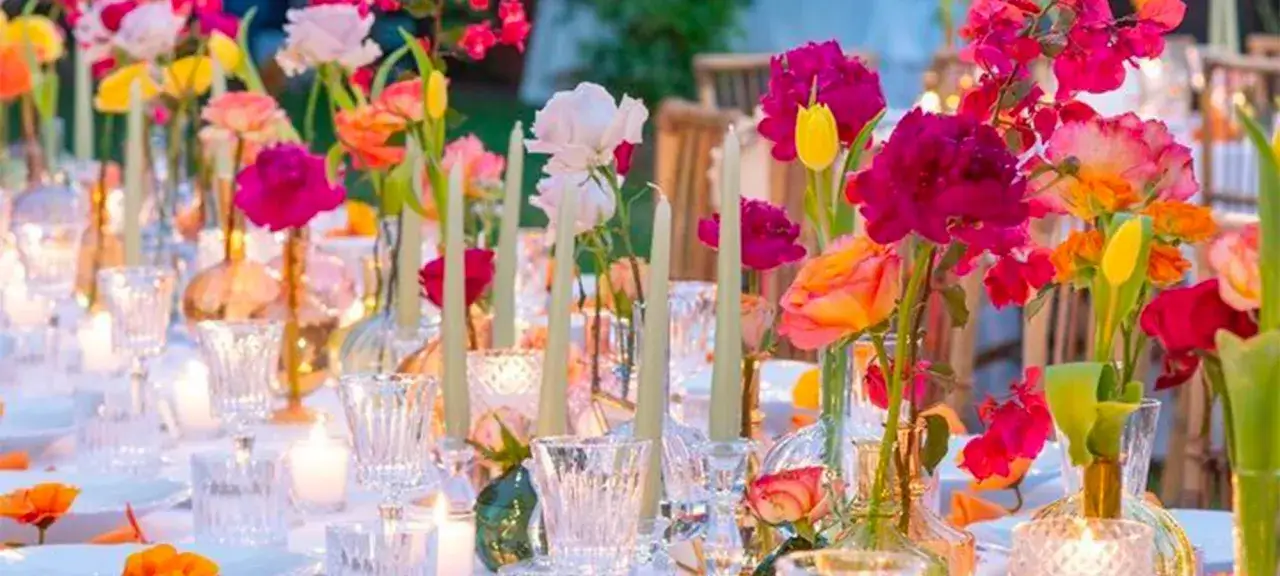 Table dressée avec des fleurs vives et des bougies. La couleur de mariage et signification se reflètent dans ce bouquet joyeux.