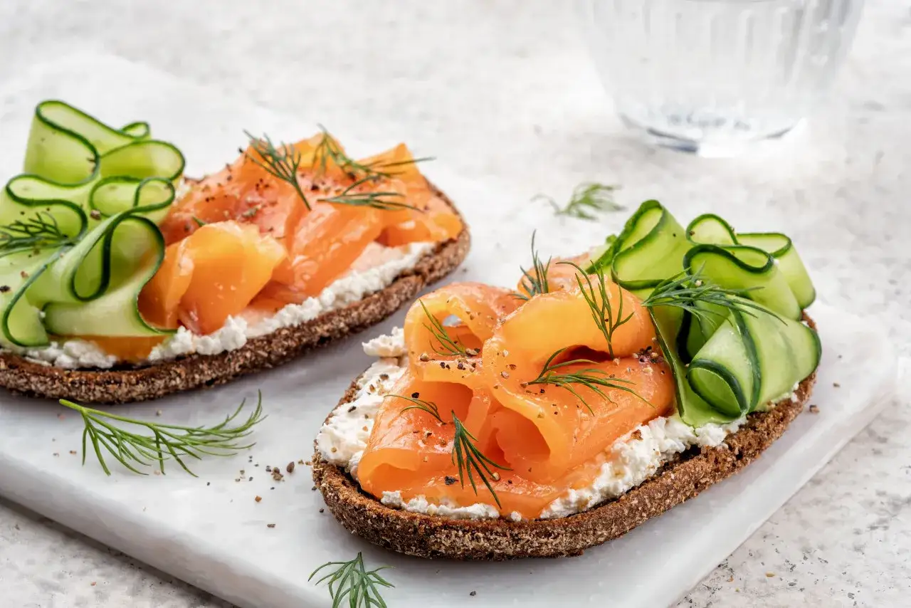 Smørrebrød con salmone affumicato, cetrioli e formaggio cremoso. Un'idea su cosa mangiare a Copenaghen per un pranzo leggero e gustoso.