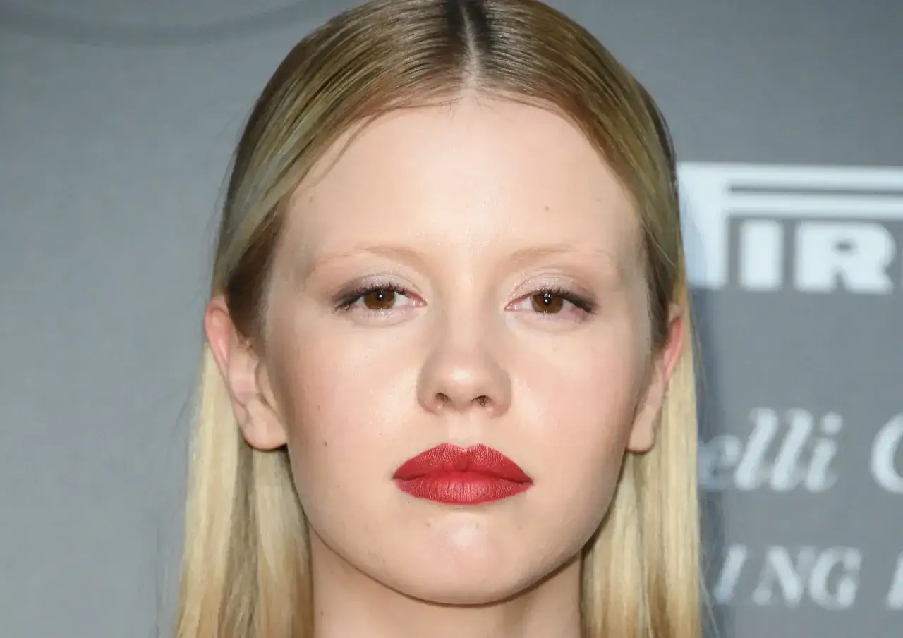 Primo piano di una giovane donna con labbra rosse audaci, capelli biondi e un'espressione intensa, come in un film di mia goth.