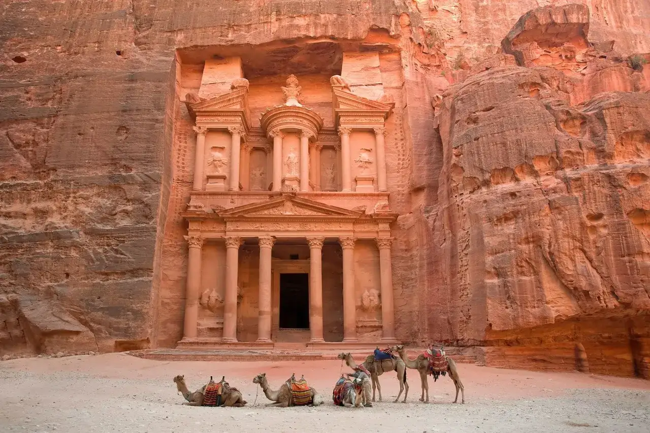 Le trésor de Petra en Jordanie, sculpté dans la roche, avec des chameaux prêts pour une aventure dans le désert.