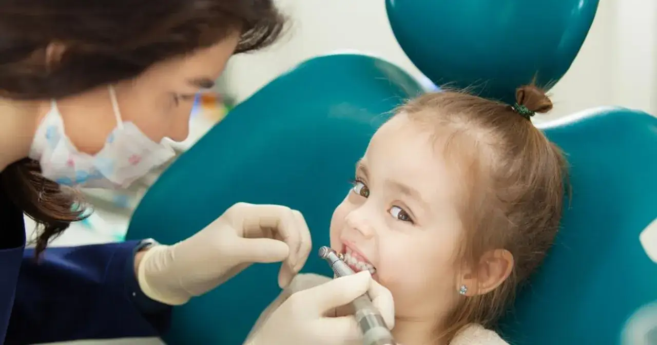 Mała dziewczynka u dentysty, która nie ma zgrzytania zębami u dziecka. Stomatolog w rękawiczkach bada jej ząbki.