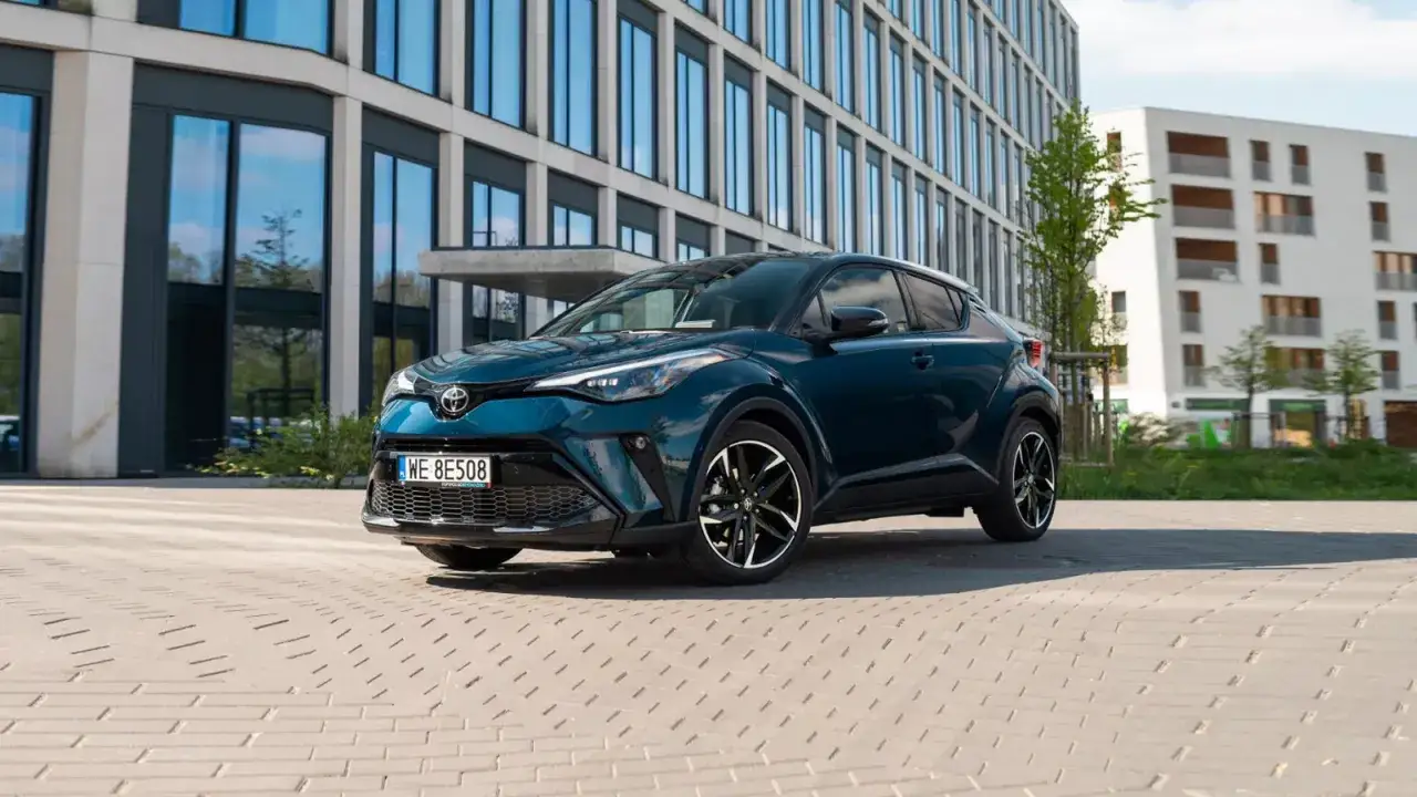 Nowoczesna Toyota hybryda w kolorze głębokiego granatu, zaparkowana przed biurowcem. Sprawdź atrakcyjną toyota hybryda cena!
