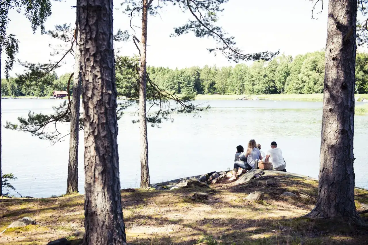 Vänner njuter av en picknick vid en sjö i Sverige under påsklovet.