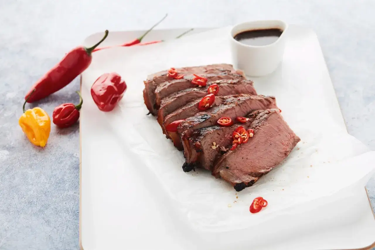Tranches de côte à l'os juteuse, garnies de piment rouge frais, accompagnées d'une sauce et de poivrons.