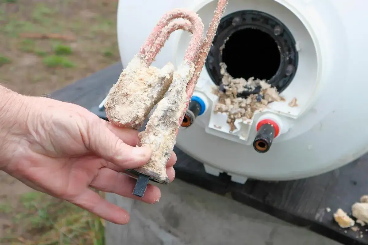 Elemento calefactor de termo con gran acumulación de sarro. Muestra la importancia de saber como limpiar un termo por dentro para evitar daños.