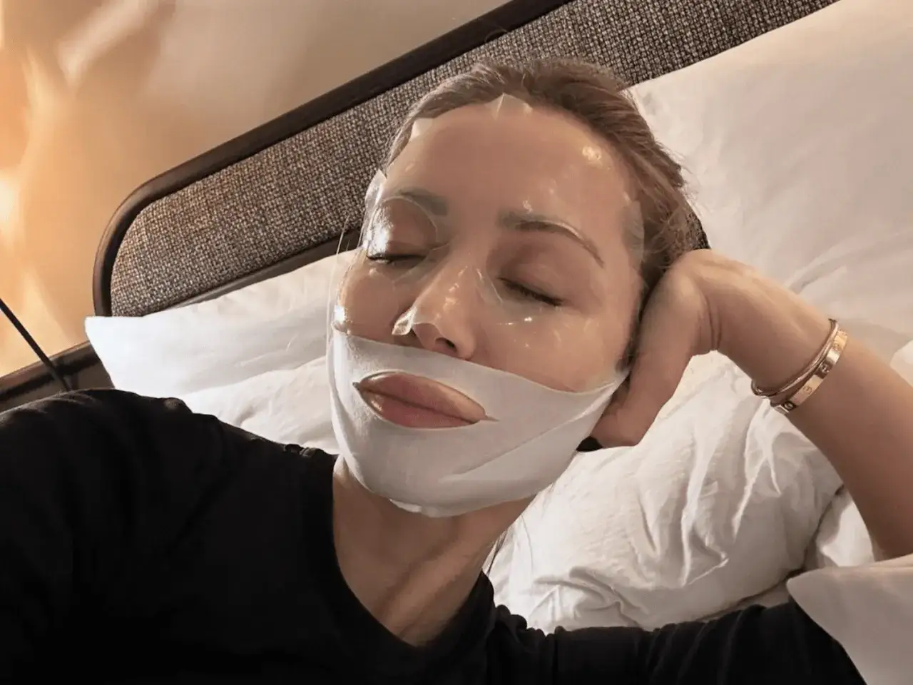 Dopo la maschera in tessuto, si lava il viso. Relax e cura della pelle in letto.