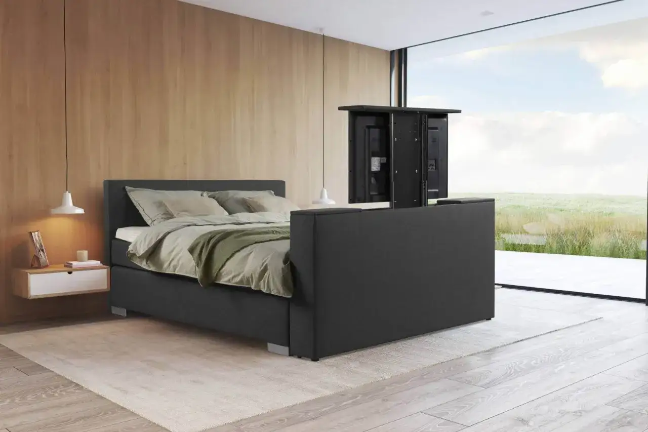 Modernes Schlafzimmer mit einem Bett, das einen versteckten Fernseher am Bettende integriert. Gem&uuml;tliche Atmosph&auml;re mit Holzwand und gro&szlig;em Fenster.