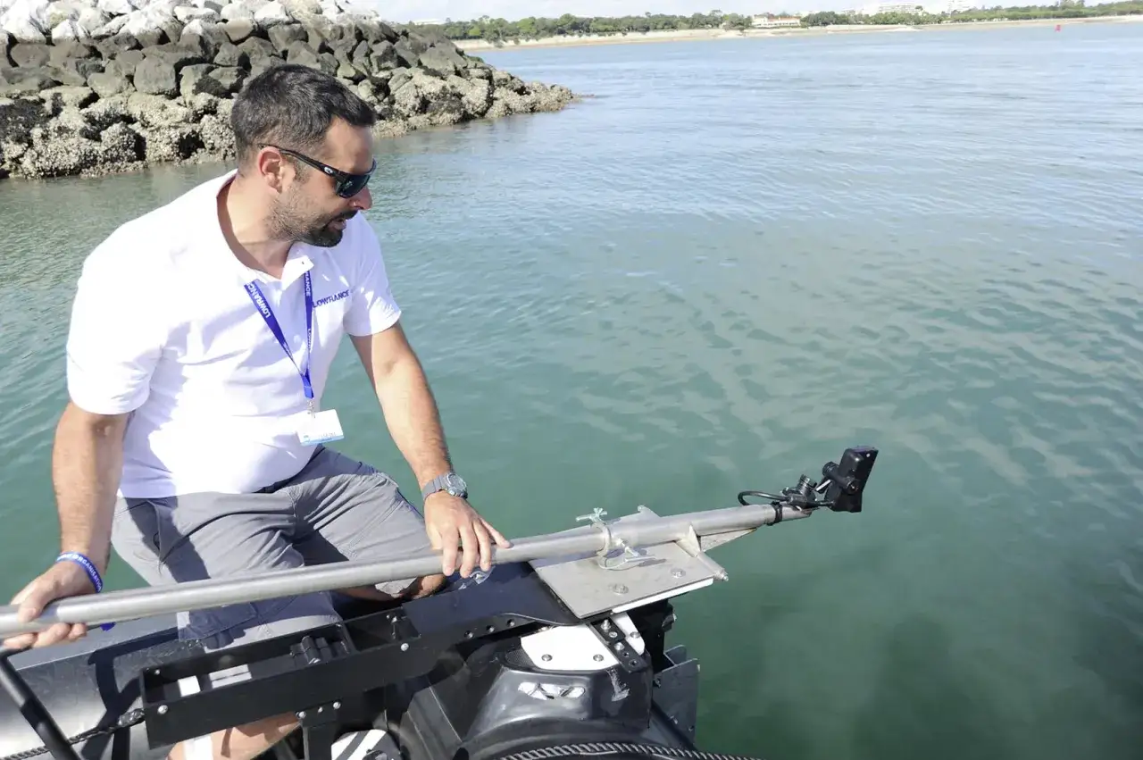 Un homme ajuste le branchement d'un sondeur Lowrance sur un bateau, prêt pour une exploration aquatique.