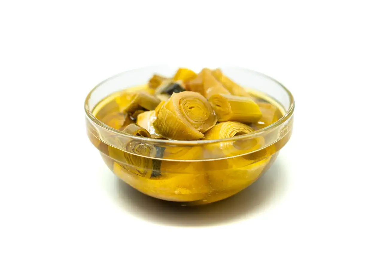 Cuenco de cristal con puerros confitados en aceite.