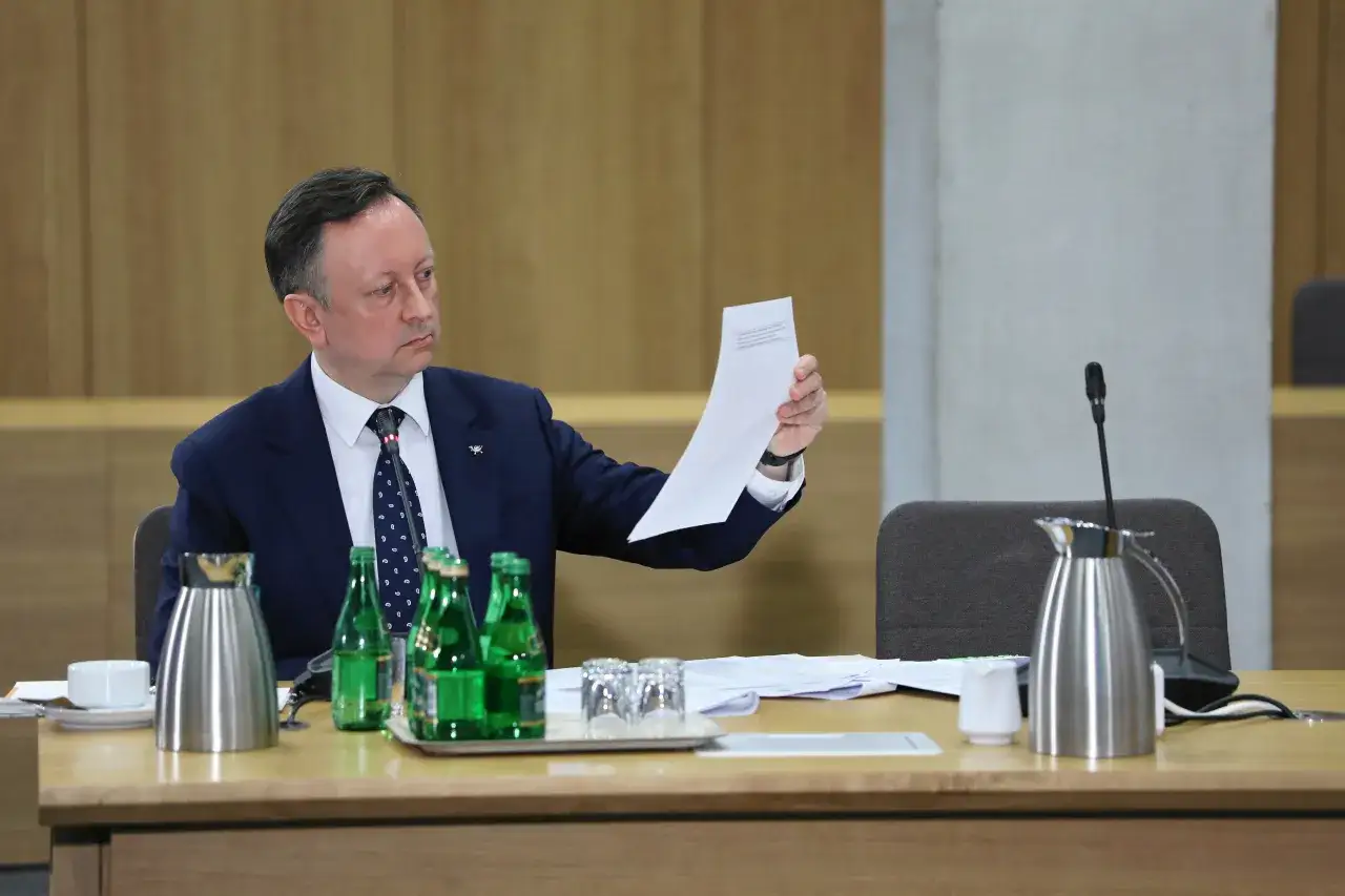 Tomasz Grodzki analizuje dokumenty, być może dotyczące Poczty Polskiej, podczas spotkania.