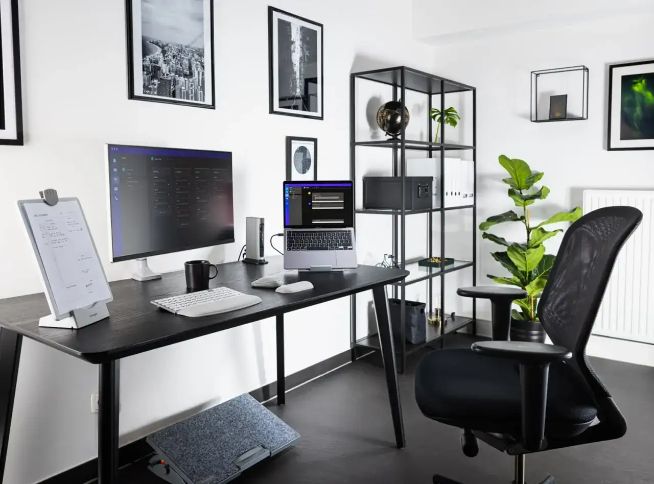 Bureau moderne pour un setup teletravail efficace : écran, ordinateur portable, clavier, souris, repose-pieds et chaise ergonomique.