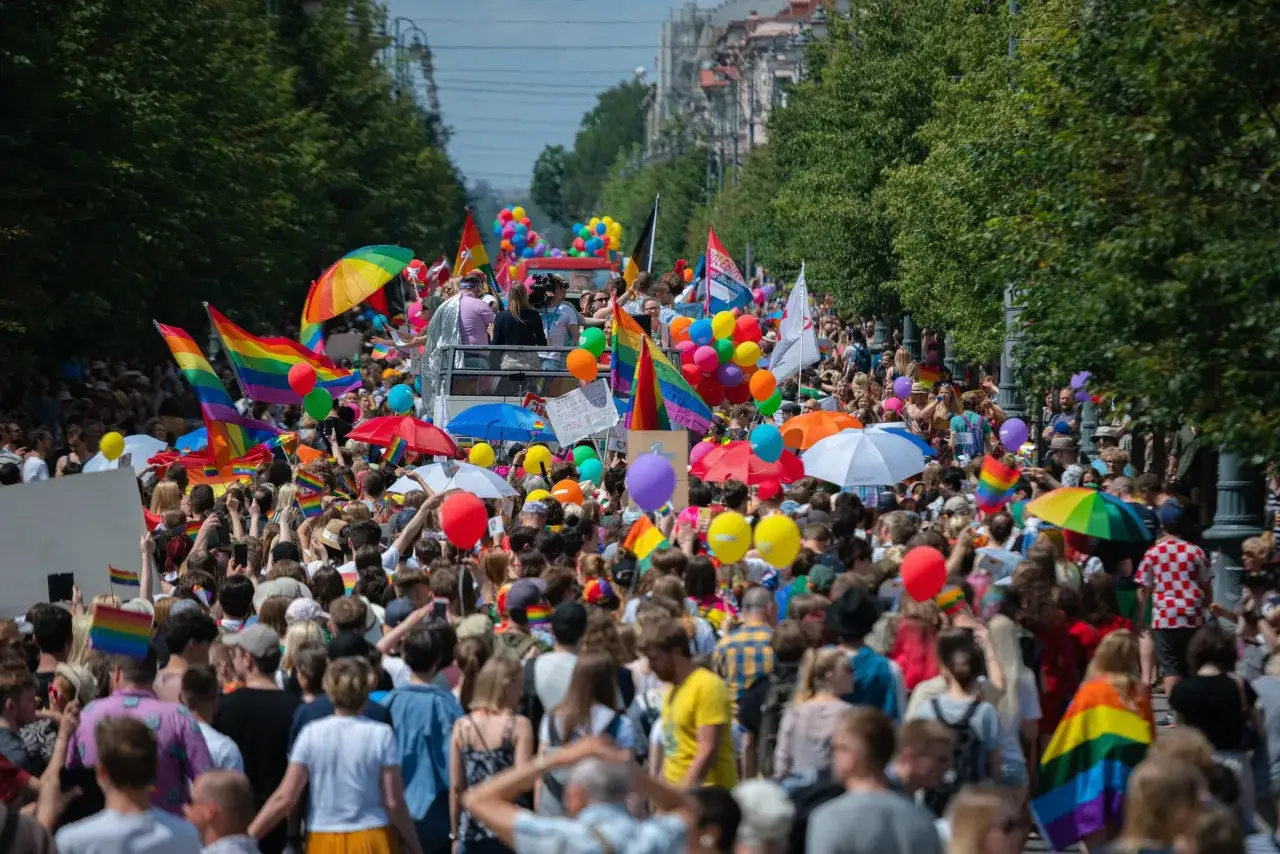 A vibrant Pride parade fills a street, with rainbow flags, balloons, and a cheering crowd. This scene captures the spirit of one of Europe's gayest cities.