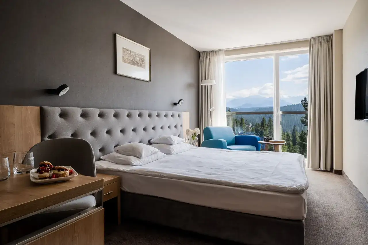 Pokój w hotelu Harnaś Wierch Buńdowy, Bukowina Tatrzańska. Łóżko, fotel i widok na Tatry.