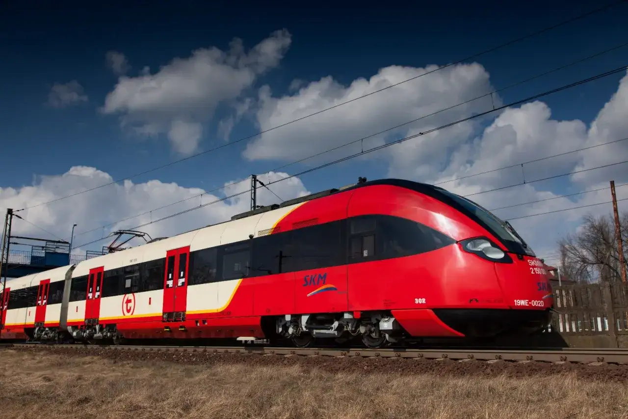 Czerwony pociąg SKM stoi na torach, czekając na usunięcie awarii w Warszawie.