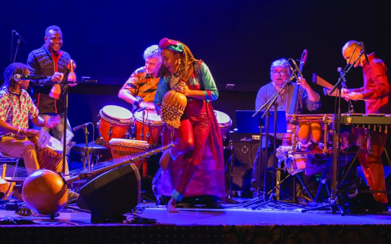 Un groupe africain connu en France, sur sc&egrave;ne, joue des percussions et d'autres instruments, cr&eacute;ant une ambiance festive.