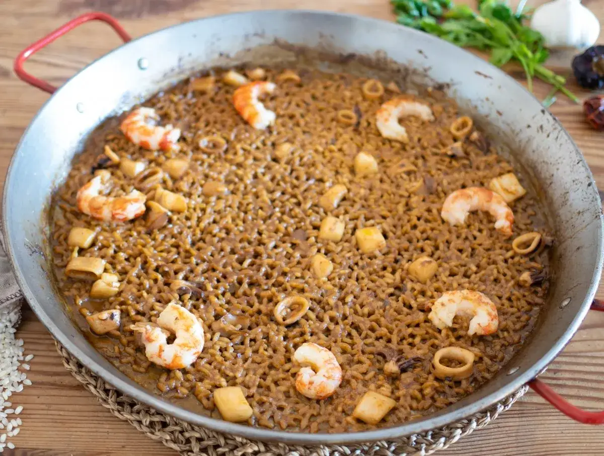Arroz del senyoret en paellera, con gambas, calamares y trozos de pescado. Un plato delicioso y listo para disfrutar.