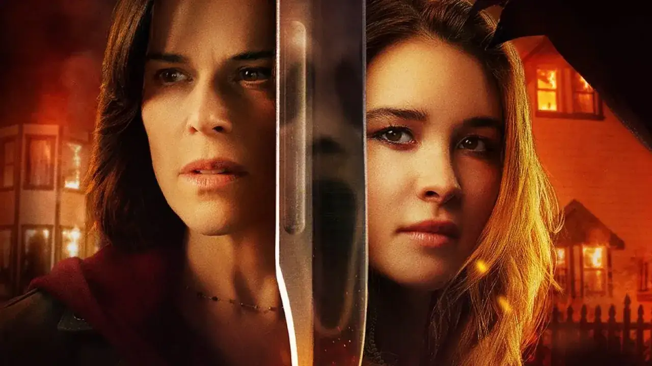 Dos mujeres, una con expresión de terror, y un cuchillo reflejan el peligro inminente en Scream 7. Casas en llamas al fondo.