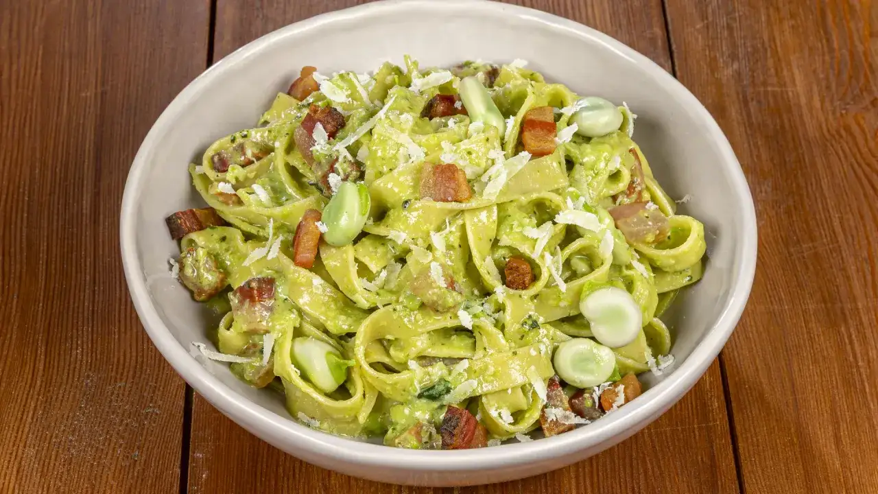 Un piatto di pasta fresca con fave, pancetta croccante e pecorino grattugiato, un classico sapore italiano.