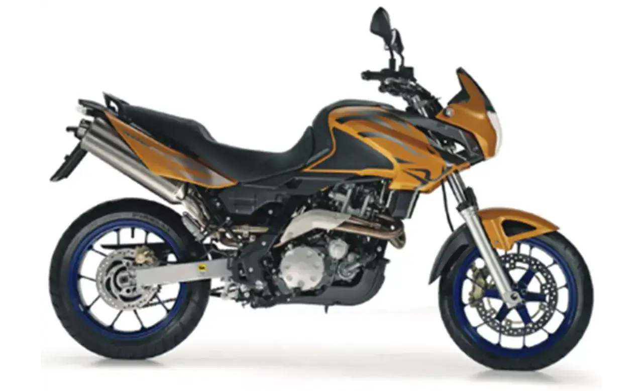 Pomarańczowy motocykl Aprilia Pegaso 650 z czarnym siedzeniem i niebieskimi felgami, gotowy na przygodę.