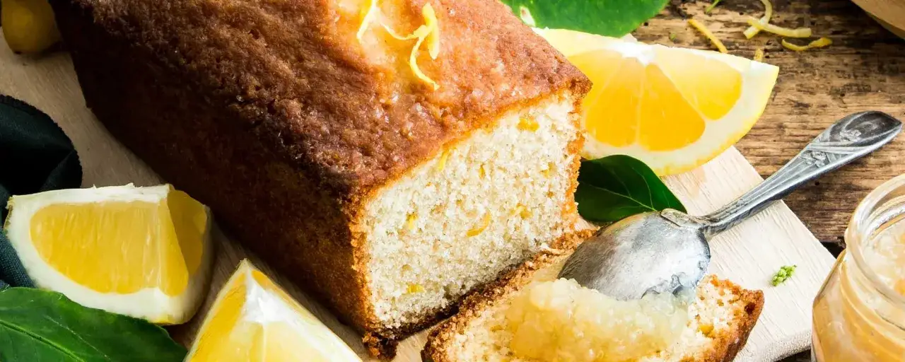 Gâteau moelleux au citron, garni de zestes et servi avec une cuillère de confiture de citron à la mentonnaise.