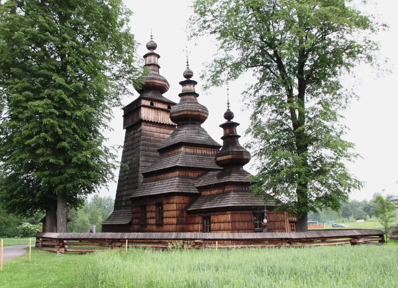 Drewniana cerkiew, jeden z pięknych polskich monuments, otoczona zielenią.