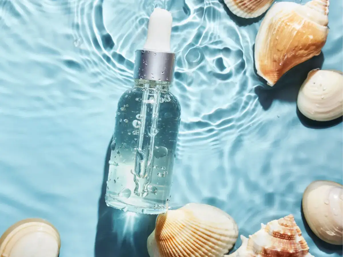 Kropla czystości w wodzie, otoczona muszlami. To esencja biomarine, która odżywia skórę.