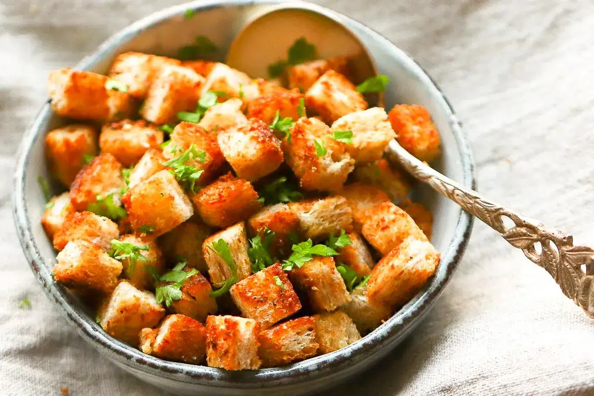 Goldbraune, knusprige Croutons, frisch zubereitet, garniert mit Petersilie in einer Schale. Perfekt zum Salat oder Suppe. #croutonsselbenmachen