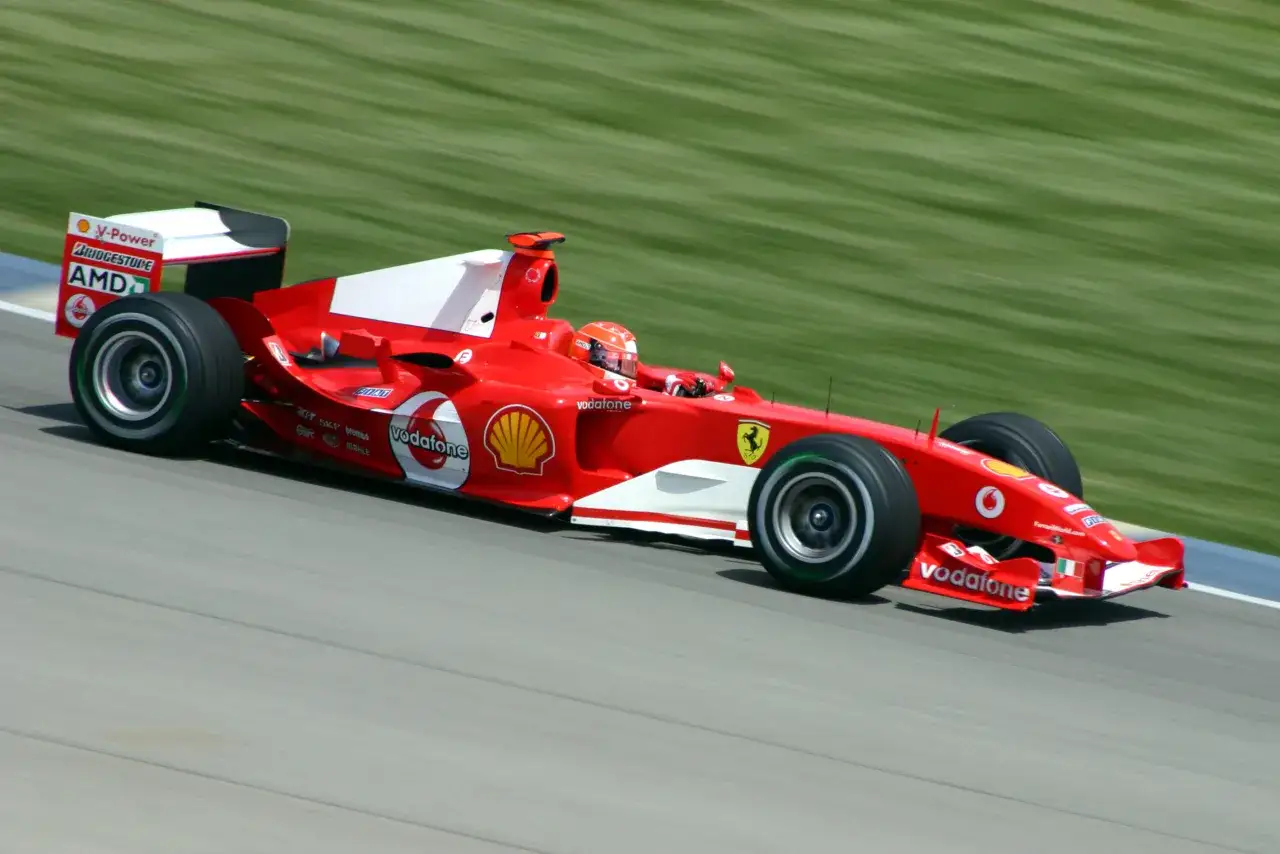 Czerwony bolid Ferrari z logo Vodafone, za kierownicą siedzi były brazylijski kierowca Formuły 1.