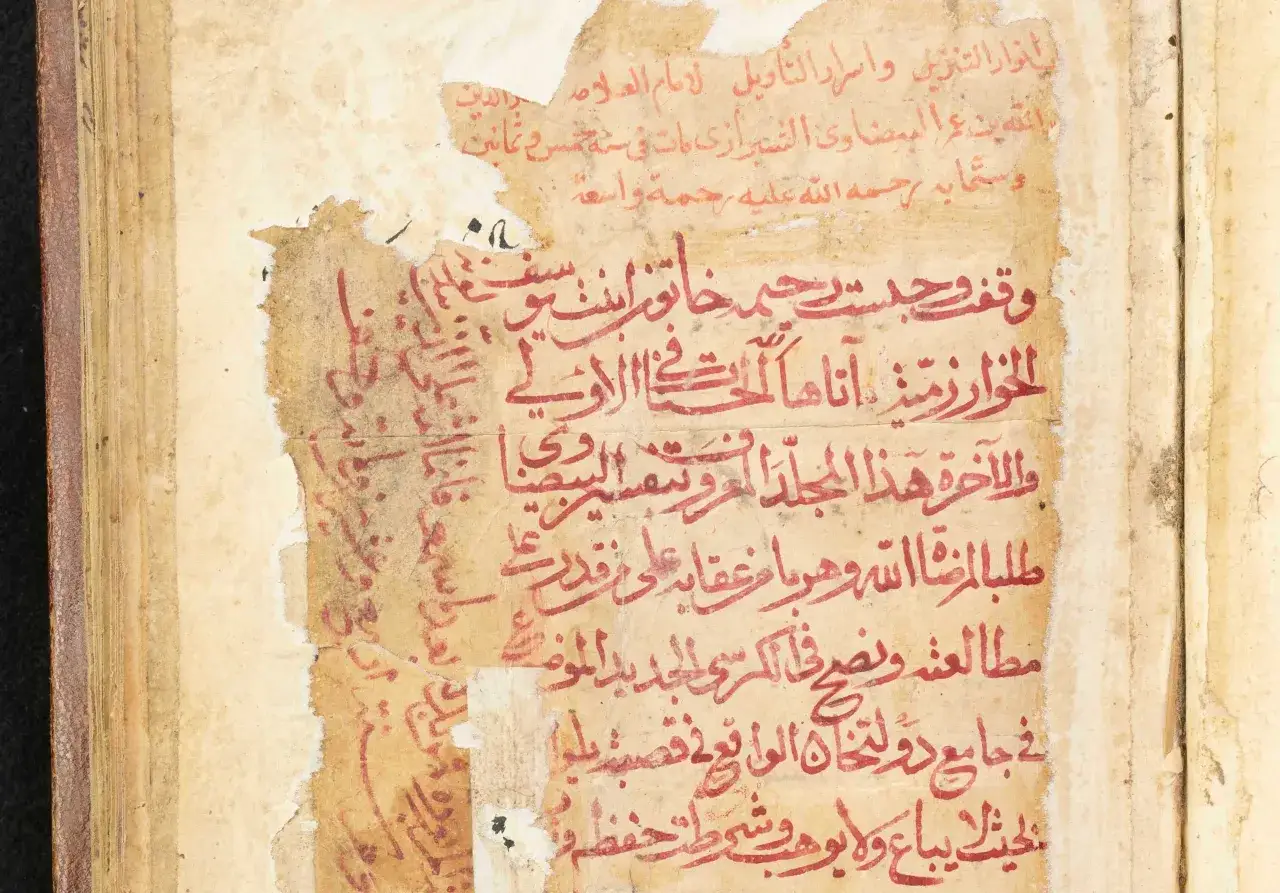 Altes Manuskript mit roten arabischen Schriftzeichen. Die Frage, wer hat den Koran geschrieben, wird hier nicht beantwortet, aber der Text stammt aus einer alten islamischen Schrift.