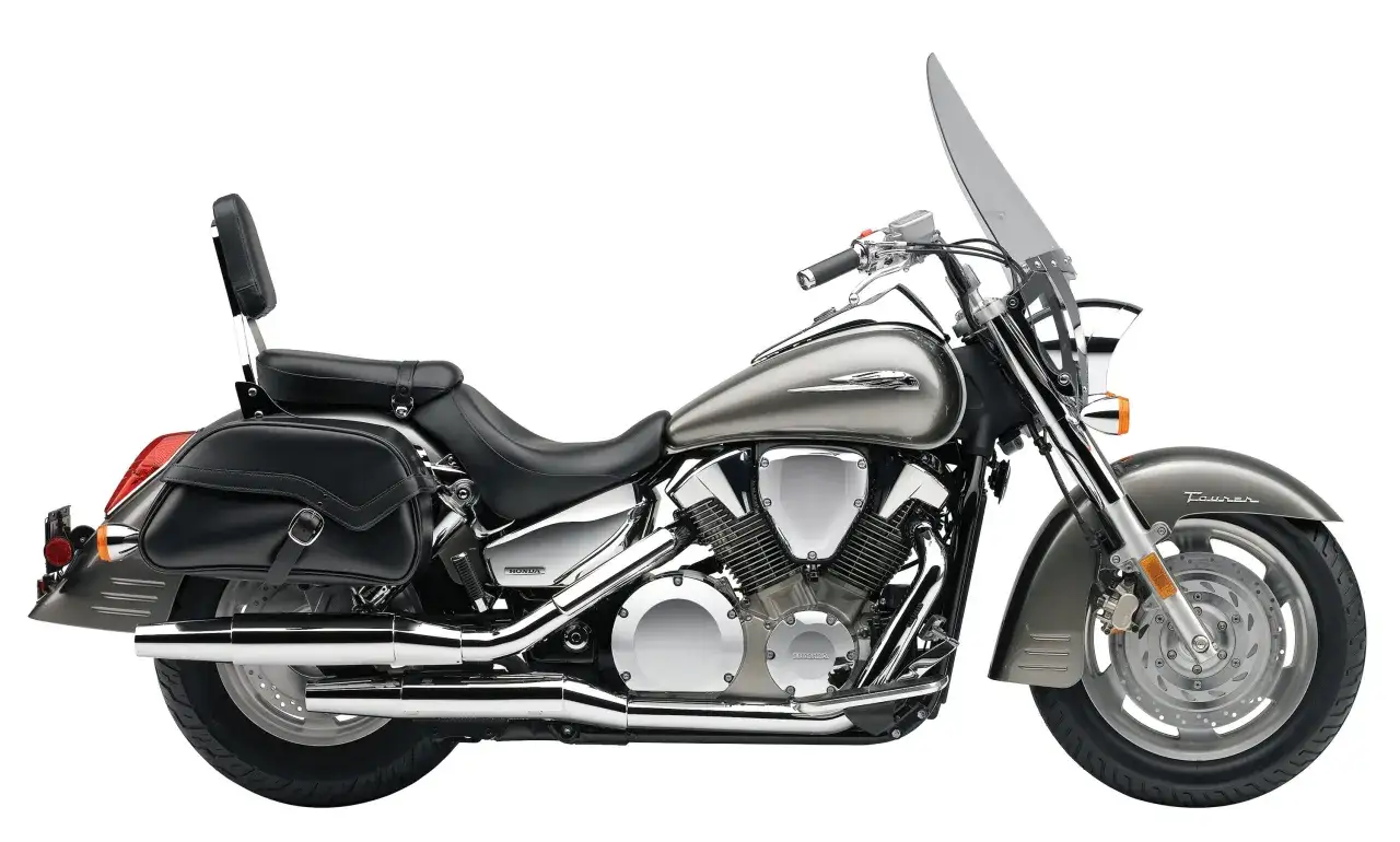 Srebrny motocykl Honda VTX 1300 z czarnymi sakwami i wysoką szybą.
