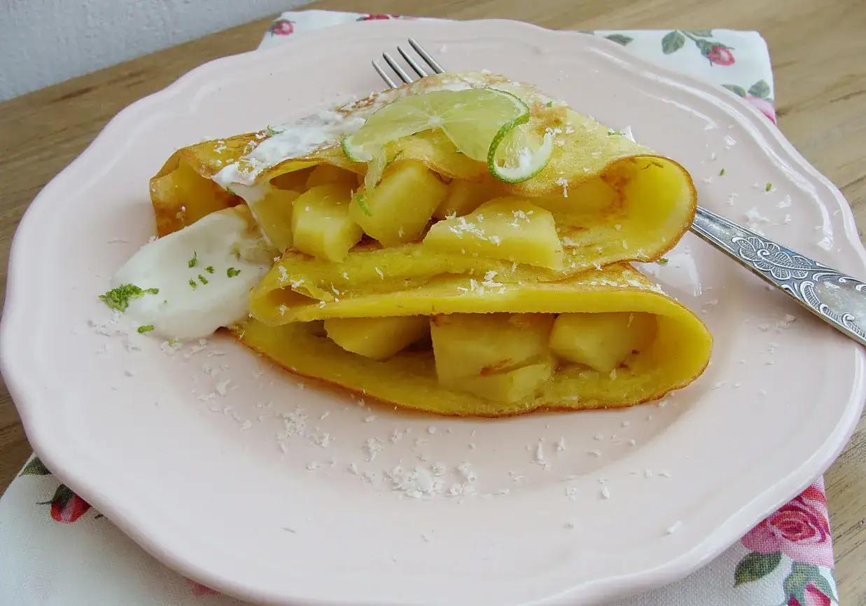 Pyszne naleśniki z mąki kokosowej z kawałkami ananasa, bitą śmietaną i plasterkami limonki.