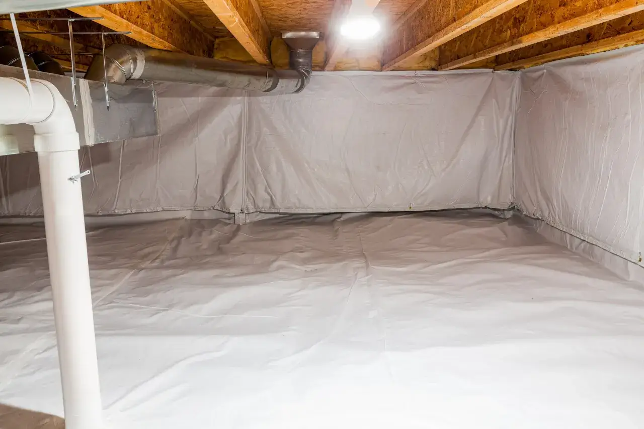 A clean crawl space with a white vapor barrier on the floor and walls, protecting against moisture.