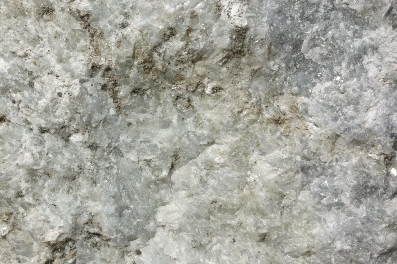 Nahaufnahme von weißem Marmor mit grauen Einschlüssen, die seine einzigartigen Marmor Eigenschaften zeigen.