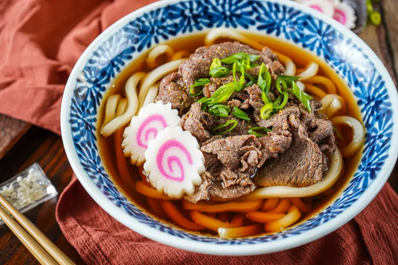 Herzhafte Udon-Nudeln mit Rindfleisch, Frühlingszwiebeln und Fischkuchen in Brühe.