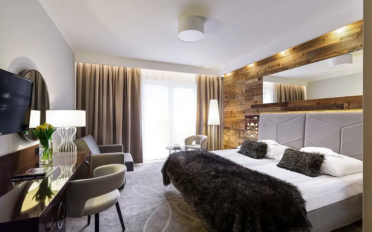 Przytulny pokój hotelowy w Karpaczu, idealny na **karpacz weekend we dwoje**. Drewniana ściana, wygodne łóżko i stylowe meble.