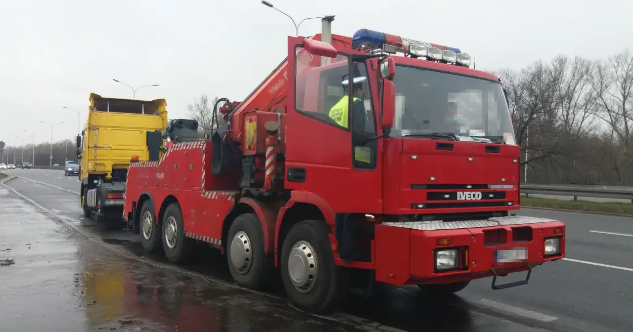 Czerwony holownik Iveco z żółtą naczepą, gotowy do akcji. Dofinansowanie na pomoc drogową ułatwia takie działania.