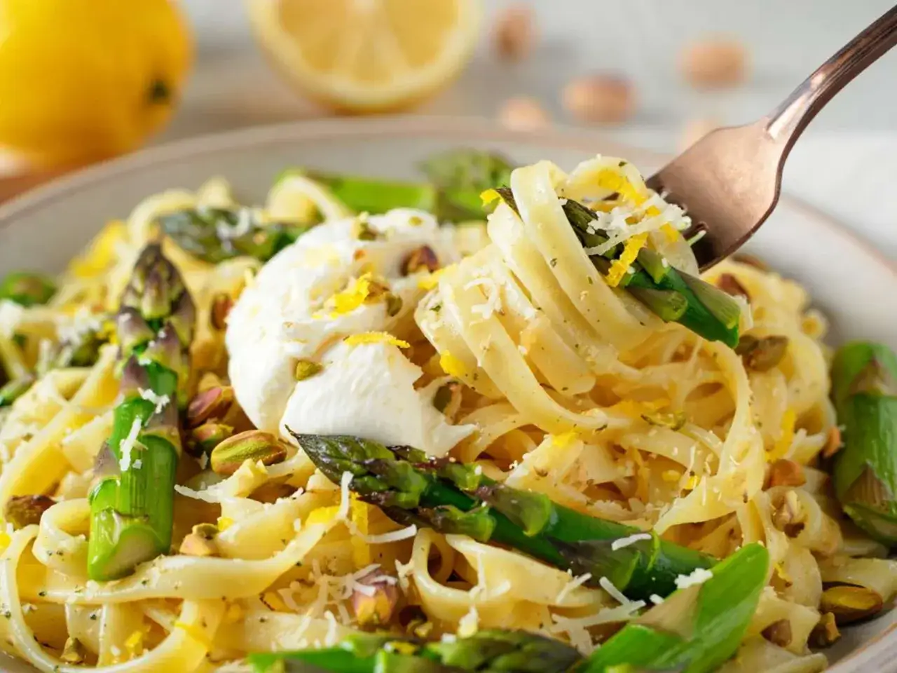 Spaghetti mit Spargel, garniert mit Burrata, Pistazien und Zitronenschale. Ein k&ouml;stliches Fr&uuml;hlingsgericht.