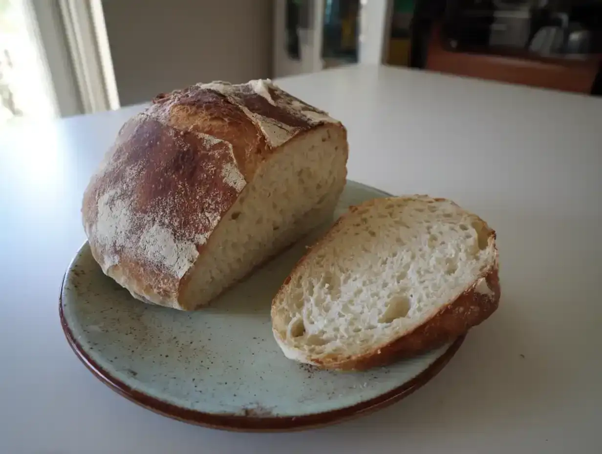 Nybakad ciabatta, perfekt för ditt nästa ciabatta recept. En skiva ligger på en ljusblå tallrik bredvid ett halvt bröd.