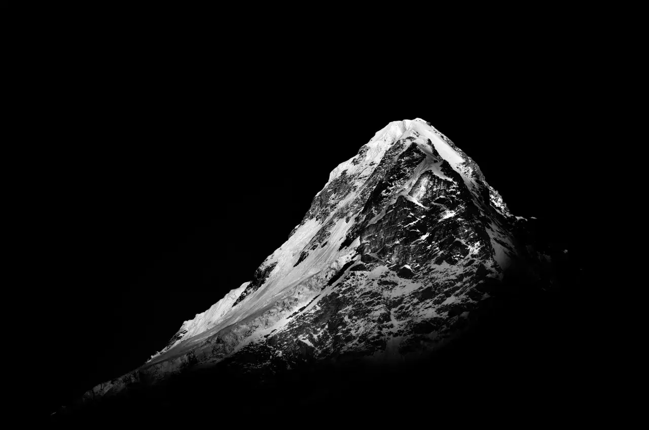 Pico nevado en **blanco y negro photoshop**, con sombras profundas y texturas rocosas y heladas.