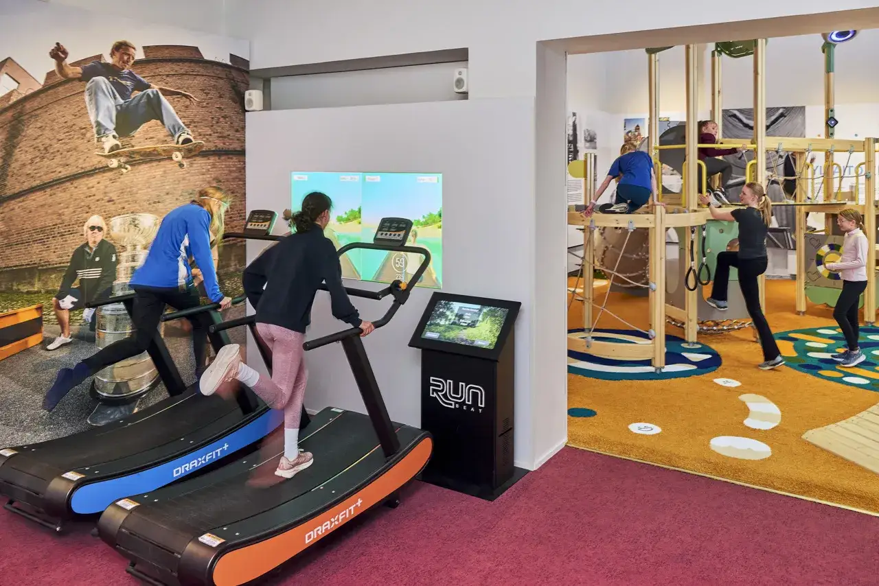 Niños corriendo en cintas de correr y jugando en una estructura de juegos en Helsinki. ¡Diversión activa para toda la familia!