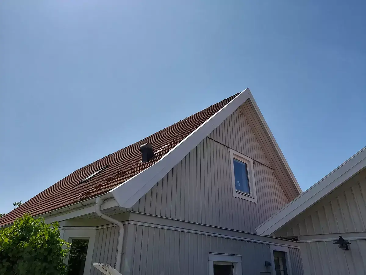Vitt och fr&auml;scht f&ouml;r att m&aring;la vindskivor p&aring; ett hus under en klarbl&aring; himmel.