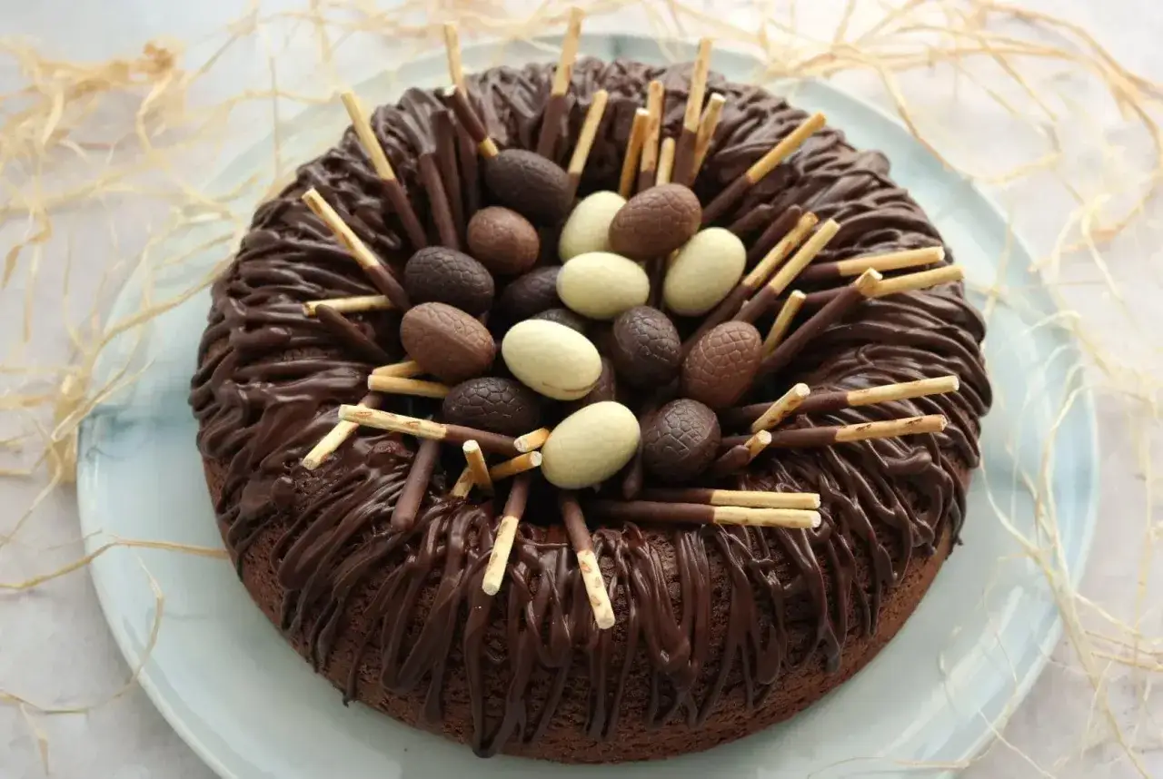 Gâteau au chocolat décoré comme un nid de Pâques, garni d'œufs en chocolat et de bâtonnets.