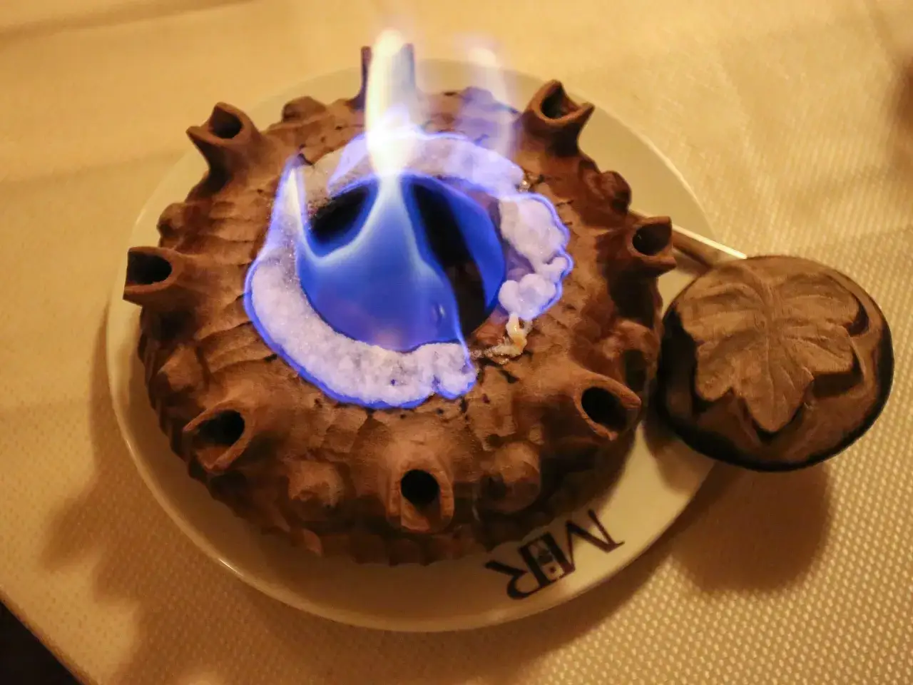 Un tradizionale caffè alla valdostana in fiamme, servito in una coppa di legno con manici a forma di corno.