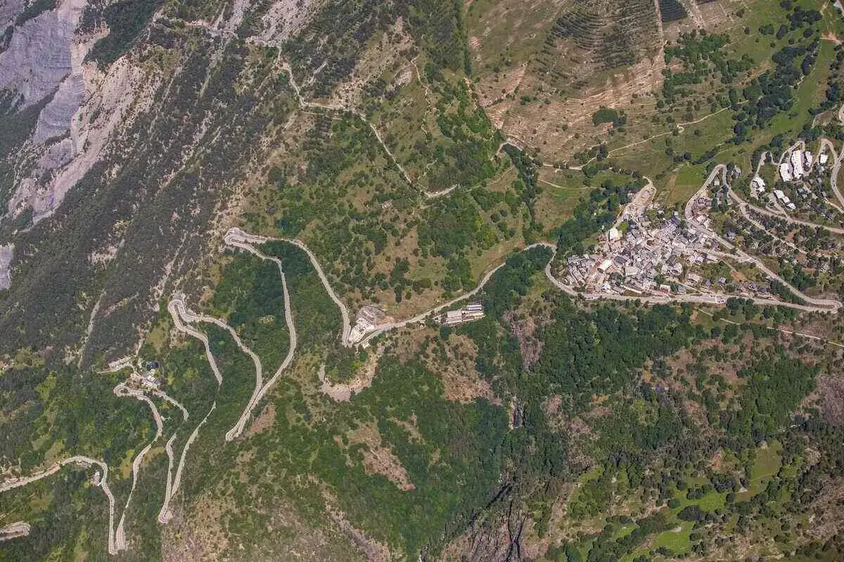 Vista aerea della famosa salita all'Alpe d'Huez, con tornanti serpeggianti che conducono a un villaggio alpino.