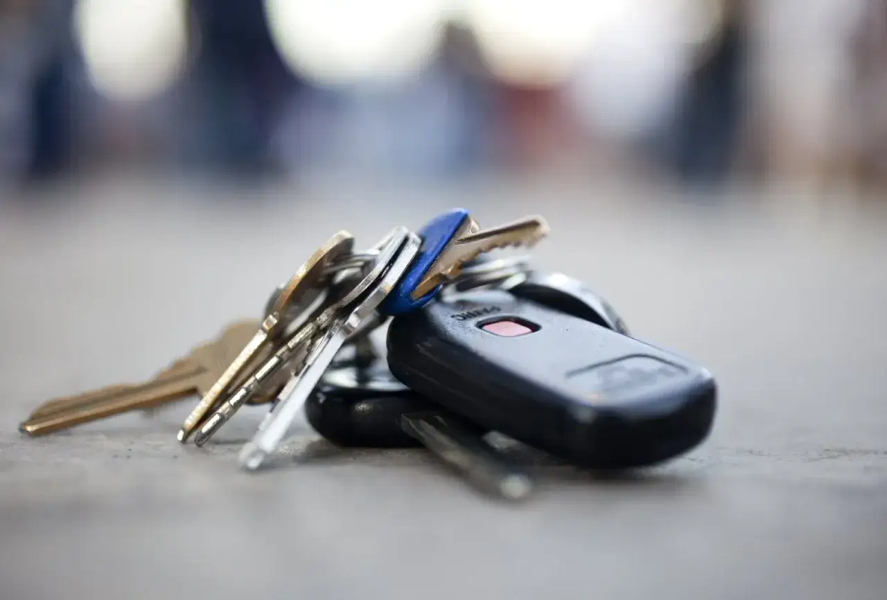Un manojo de llaves, incluyendo un mando a distancia de coche, descansa sobre una superficie gris. ¡Ay, he perdido las llaves del coche!