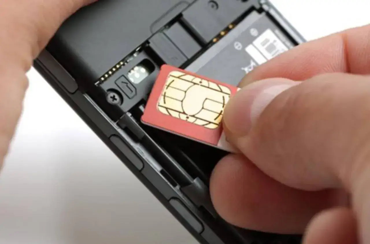 Inserimento di una SIM card nel telefono. Il numero seriale SIM è visibile sul chip dorato.