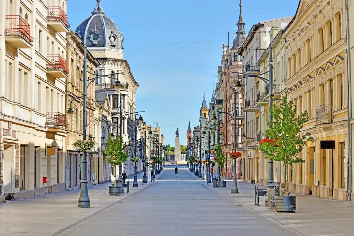 Prachtvolle Architektur s&auml;umt eine breite Stra&szlig;e in **Ł&oacute;dź, Polen**. Ein Denkmal am Ende der Allee verspricht eine spannende Entdeckungstour.