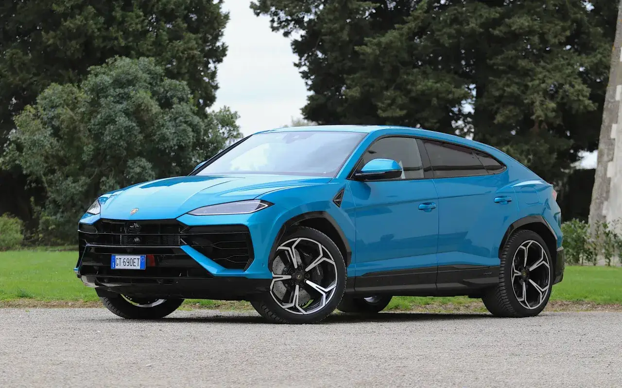 Niebieski Lamborghini Urus na tle drzew. Zastanawiasz się, ile pali lamborghini? Ten SUV potrafi zaskoczyć!