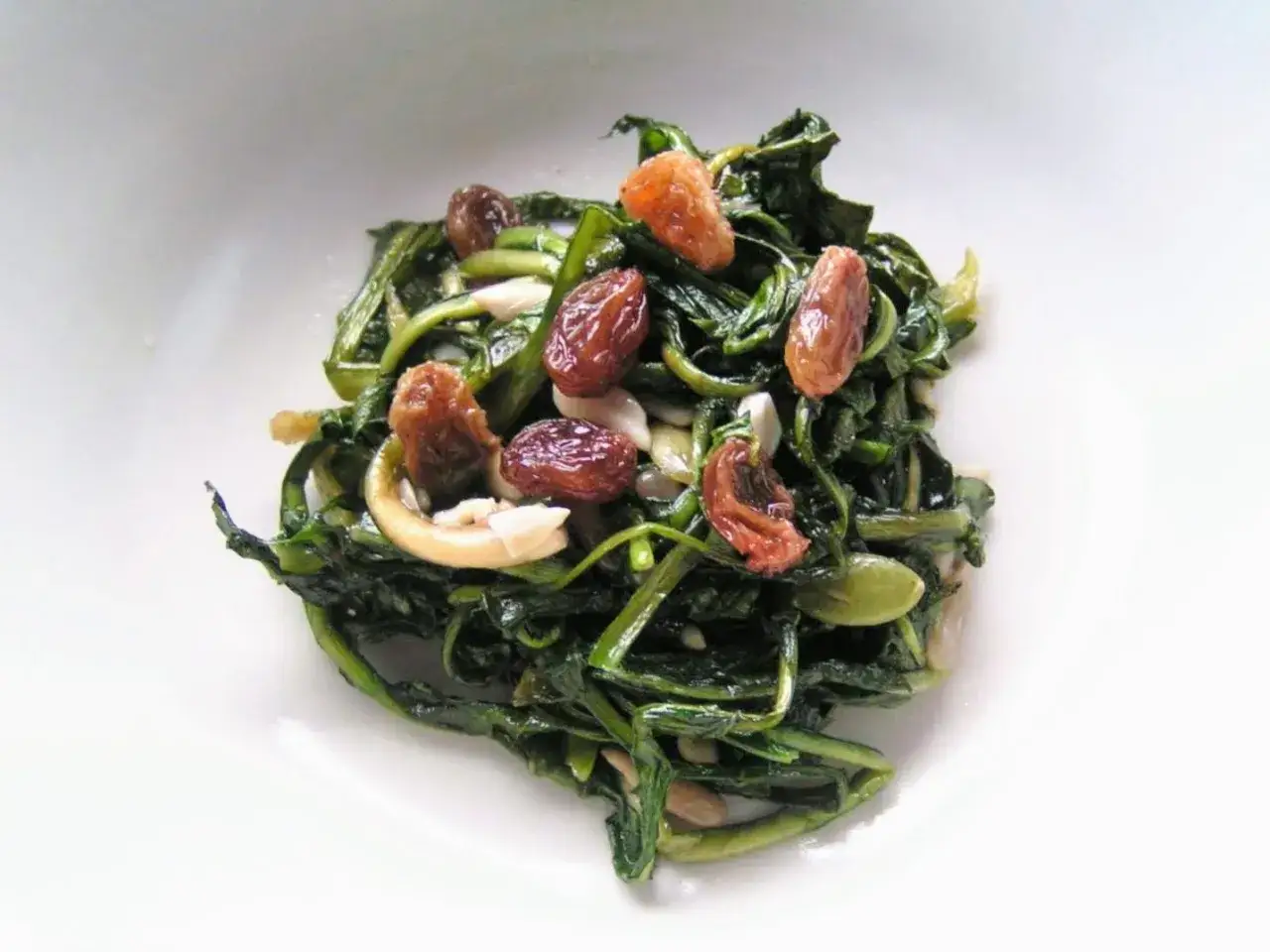 Insalata di tarassaco foglie con uvetta e pinoli, un piatto colorato e gustoso.